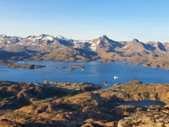 Landskabsbillede af bjerge med sne på toppen og blåt vand. Vejret er klar, så himlen er også blå.