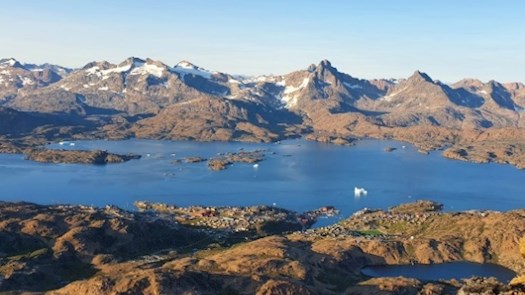 Landskabsbillede af bjerge med sne på toppen og blåt vand. Vejret er klar, så himlen er også blå.